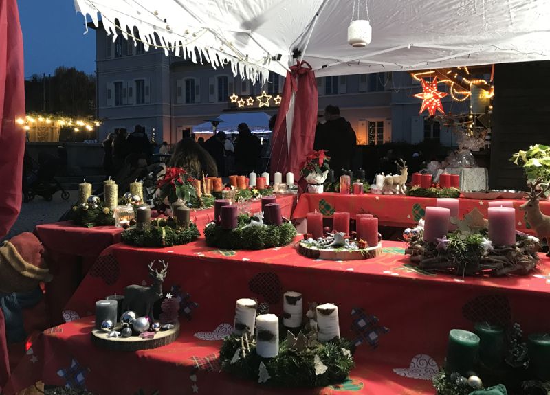 Ein Stand auf dem Weihnachtsmarkt mit Adventskränzen und Kerzen