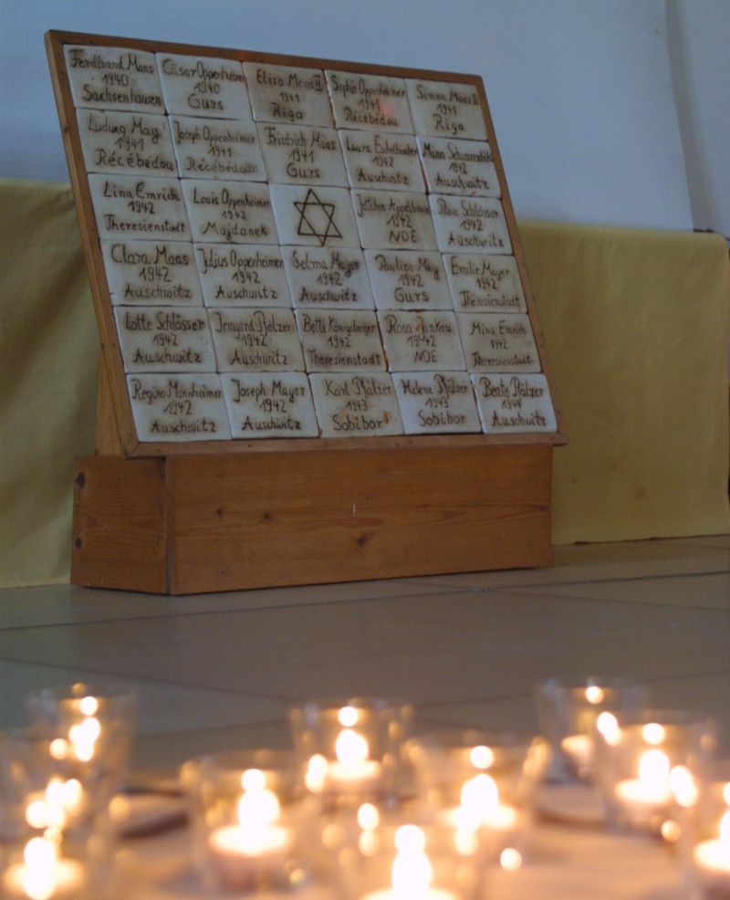 Gedenktafel mit den Namen der deportierten Hemsbacher Juden und davor brennende Kerzen