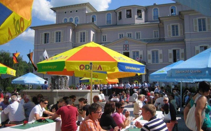 Eröffnungsfest nach der Sanierung vorm Rathaus im Sommer 2009, Bürger:innen an Bierbänken unter bunten Sonnenschirmen