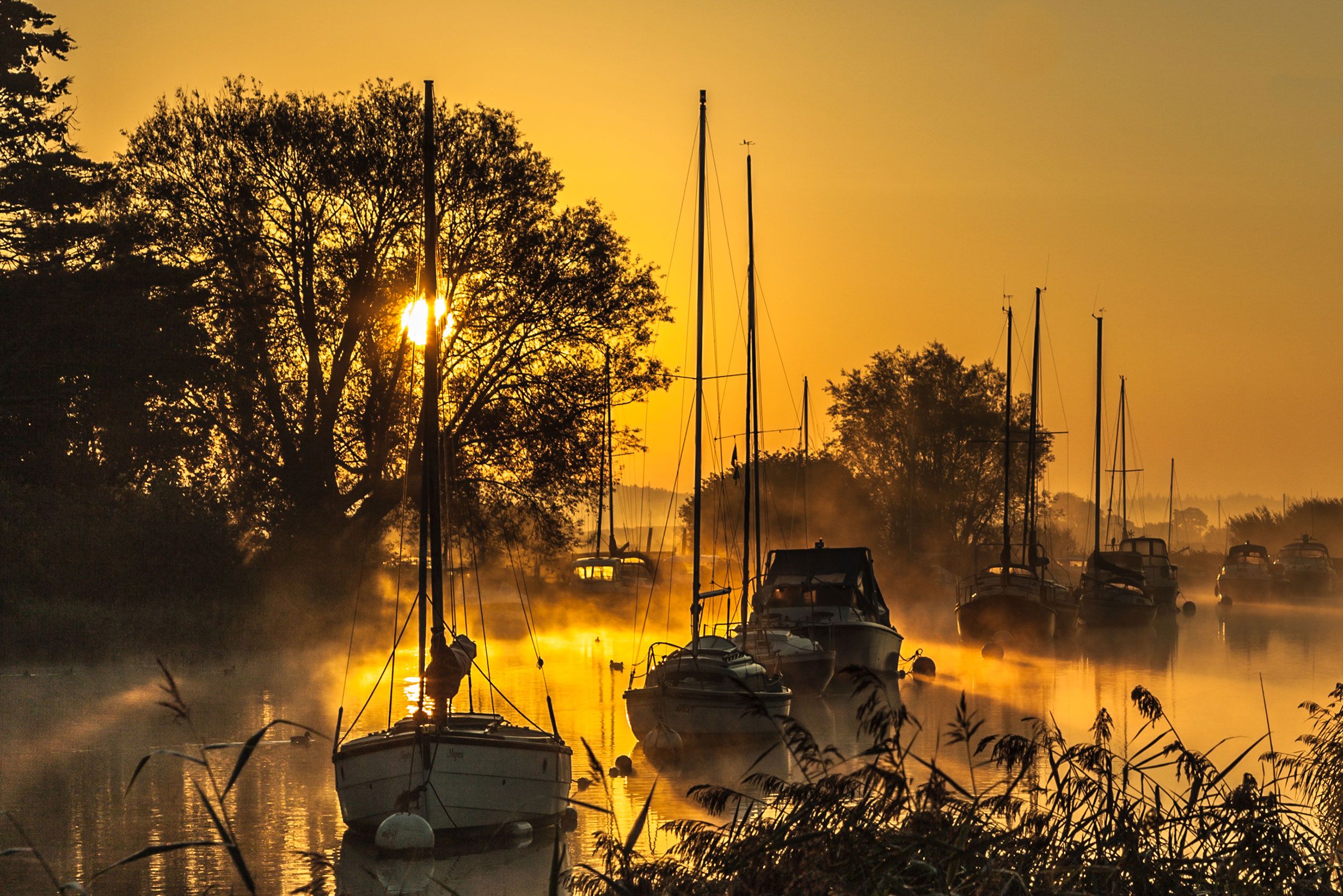 Romantisches Sonnenaufgangsbild mit Booten am Fluss von Wareham