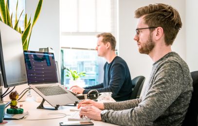 Arbeiten im Bürö, zwei männer sitzen am Schreibtisch und arbeiten an Computern